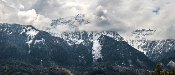 A panorama of clouds obscuring snow capped mountains in the Cascade Mountain range