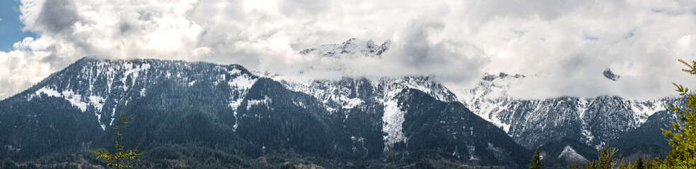 Fototapeta na wymiar A panorama of clouds obscuring snow capped mountains in the Cascade Mountain range