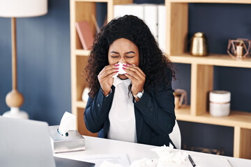 Fototapeta na wymiar Whats an entrepreneur to do when shes got the flu. Shot of a young businesswoman blowing her nose with a tissue at her desk in a modern office.