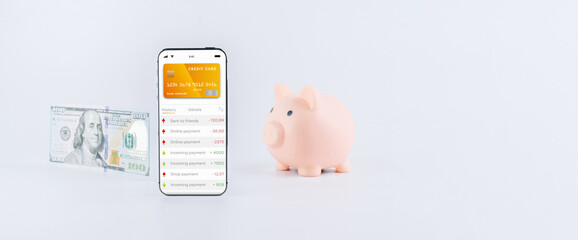 E banking concept. Mobile phone with internet online bank app. Pig bank with hundred dollar bill on white background. Online wallet save money.