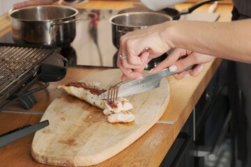 The girl cuts juicy turkey meat on a cutting board. The girl cooks dinner, prepares meat. Low calorie, diet, healthy eating. Spicy, hot