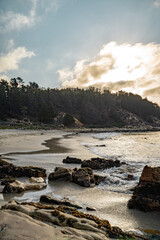 Vertical view of Cau Cau beach with forest, rocks and sea in the background.