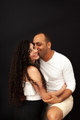 Portrait of a young couple in white t-shirts on a black background. High quality photo