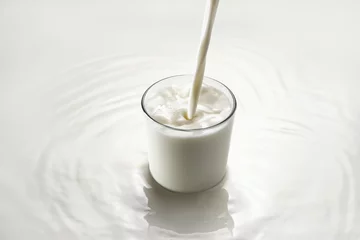 Tuinposter milk pouring into glass on white background © alter_photo
