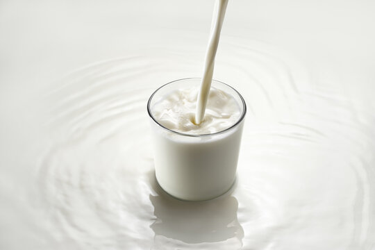milk pouring into glass on white background