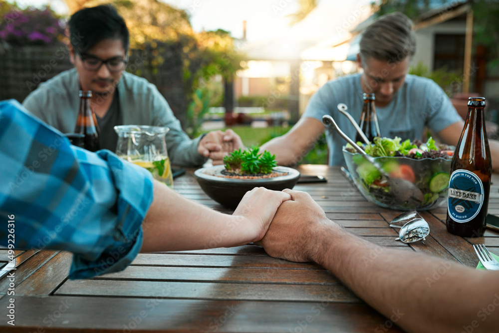 Sticker We all have so much to be thankful for. Shot of a group of young friends holding hands together around a table outside in a garden.