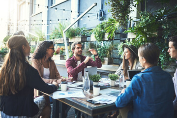 Work outside the box. Shot of a group of designers having a meeting at a coffee shop.