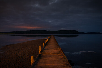 Fototapeta premium The Jasmunder Bodden coast after dark, with the pier in Lietzow, Mecklenburg-Western Pomerania, Germany