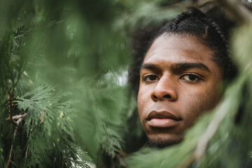 very closeup view of african american man face surrounded by pine leaves