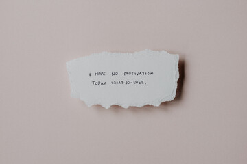 A quote about lacking motivation on a piece of scrap paper against a neutral background
