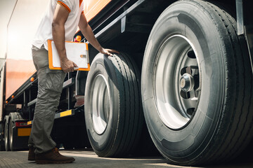 Truck Driver is Checking the Truck's Safety of Wheels and Tires. Semi TraIler Truck Inspection Maintenance Repair. Auto Repair Service Shop. 	