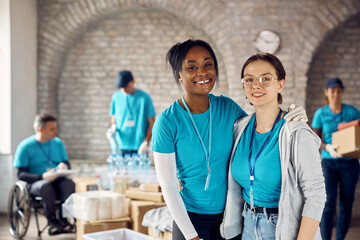 African American woman and her Caucasian friend volunteering at humanitarian aid center and looking...