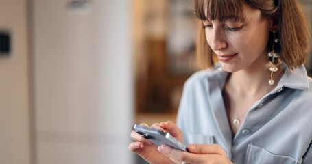 Thoughtful woman using phone at home, close-up view. Caucasian brunette girl surfing internet on smartphone - Powered by Adobe
