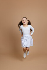 Portrait of young beautiful girl with long dark hair in white dress, socks and gymnastics shoes...