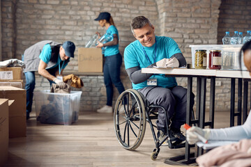 Happy man in wheelchair writing list of donations while volunteering at community center.