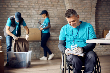 Happy volunteer in wheelchair takes notes while working at donation center.