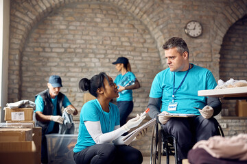 Two volunteers communicating while doing through paperwork at donation center.