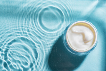 jar of beauty cream over blue water