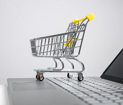 Supermarket trolley, cart at laptop. Online shopping and ecommerce concept. Using computer for remote purchases. High quality photo