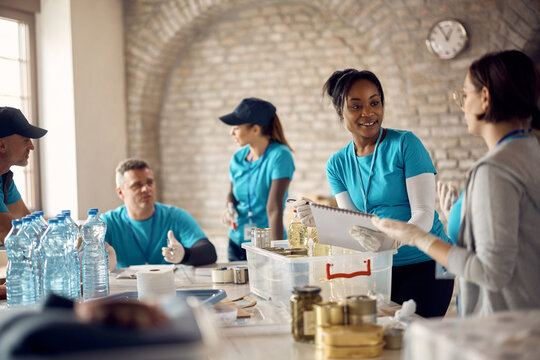 Young African American woman coordinates a group of volunteers at food bank.