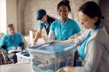 Happy volunteers packing donated clothes into boxes at community center.