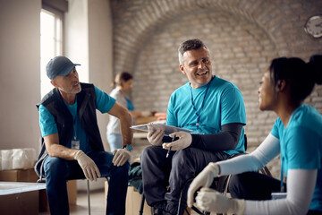 Happy coordinator in wheelchair having meeting with volunteers at humanitarian aid center.
