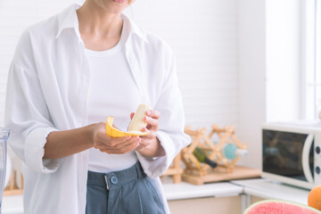 Asian woman casing banana. Beautiful woman eating a banana, at kitchen room in the morning.