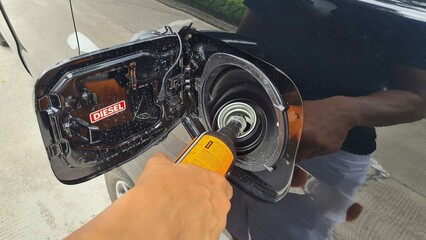 a driver fills a diesel additive into a car's diesel fuel tank to increase the cetane number and...