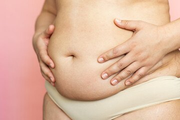 Touch woman sagging belly closeup, folds on stomach, loose skin and cellulite, obesity. Naked...