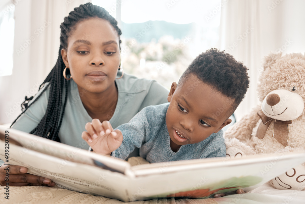 Wall mural Reading with mom. Cropped shot of an adorable little boy and his mother reading a book on a bed at home.