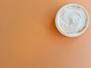 Cosmetic anti-aging cream on an orange background.