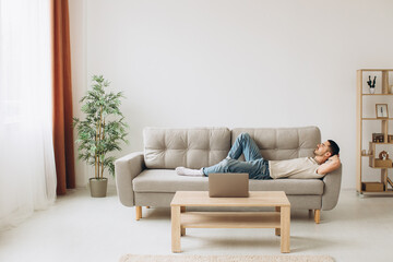 Young Man Relaxing On Sofa In Living Room