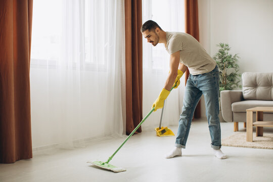 Young man washes the floor with a mop in the room