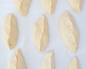 Raw pies with apple filling on a white kitchen table. Selective focus. Cooking at home concept. Tradition home-made food