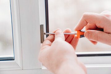 hands with a screwdriver repair, adjust or install metal-plastic windows