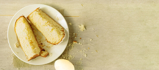 Top view, slices of sweet Easter cake on a plate and one easter egg on a light wooden background.