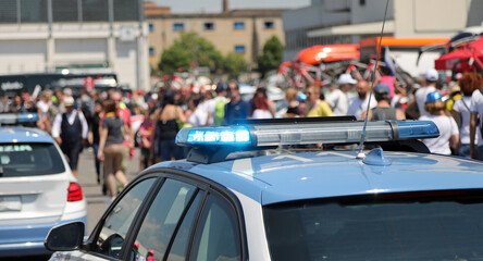 police car with flashing lights above during escort and protest demonstration of people in the street - obrazy, fototapety, plakaty