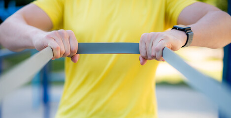 Man stretching with elastic rubber during street workout