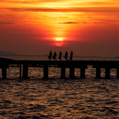 Naklejka na ściany i meble Monk walk on the bridge at sunset in evening near the beach.