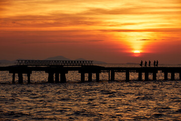 Fototapeta premium Monk walk on the bridge at sunset in evening near the beach.