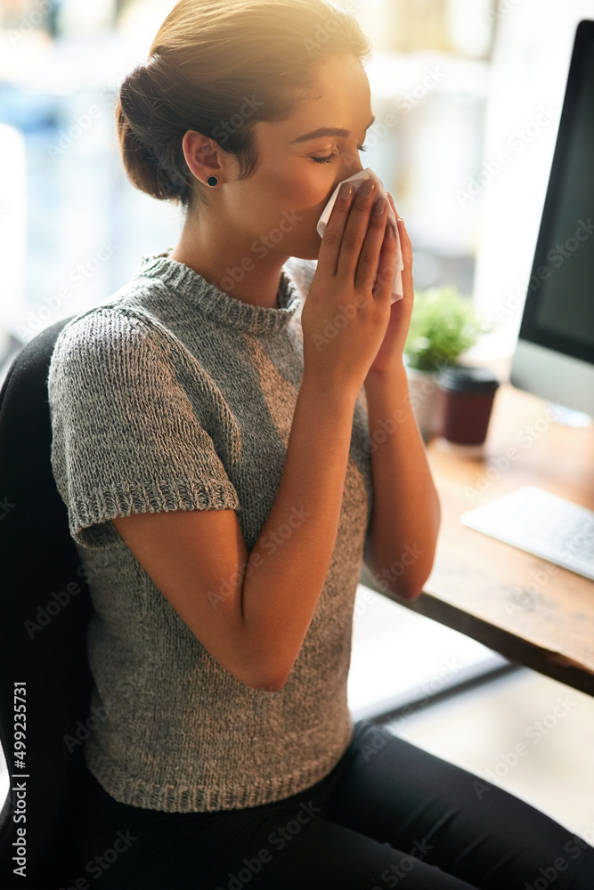 Canvas Prints Its that time of the year. Shot of a young businesswoman blowing her nose in an office.