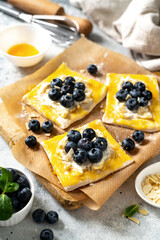 Raw puff pastry with cheese cream and blueberries. The process of making delicious sweet buns or mini pies	
