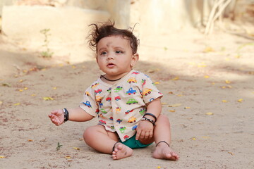 portrait photo of A small newborn cute Hindu baby sitting on the ground outside