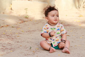 portrait photo of A small newborn cute Hindu baby sitting on the ground outside with smiling face