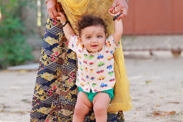 portrait photo of A small newborn cute Hindu baby walking holding the mother's hand with smiling face