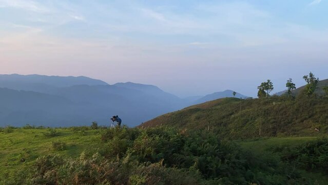 Hiker taking pictures of beautiful landscape mountain peak with morning mist atmosphere at Tak Province, Thailand. location sign in Thai language translate in English is be Viewpoint Monsisahai.