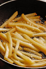 Frying french potatoes on frying oiled pan.