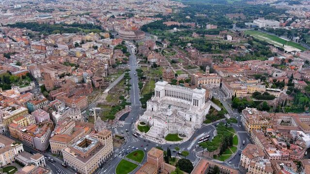 Aerial view of Altar of the Fatherland by Piazza Venezia and Colosseum in Rome, Italy. Flying drone view of white marble memorial monument and above view of iconic ancient national landmarks in 4K