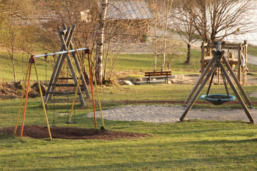 Fototapeta premium Playground with swing in early spring and meadows and sand in the background