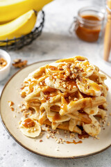 Banana waffles with walnuts and salted caramel in a plate on a culinary background	